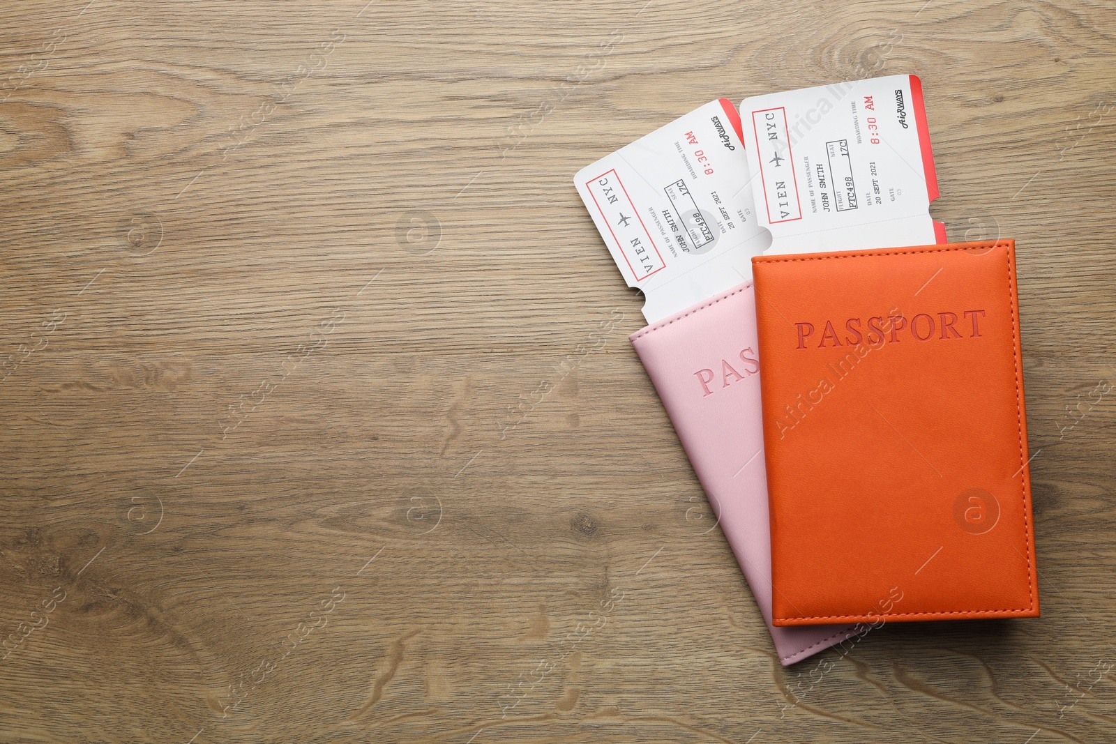 Photo of Travel agency. Flight tickets and passports on wooden table, top view. Space for text