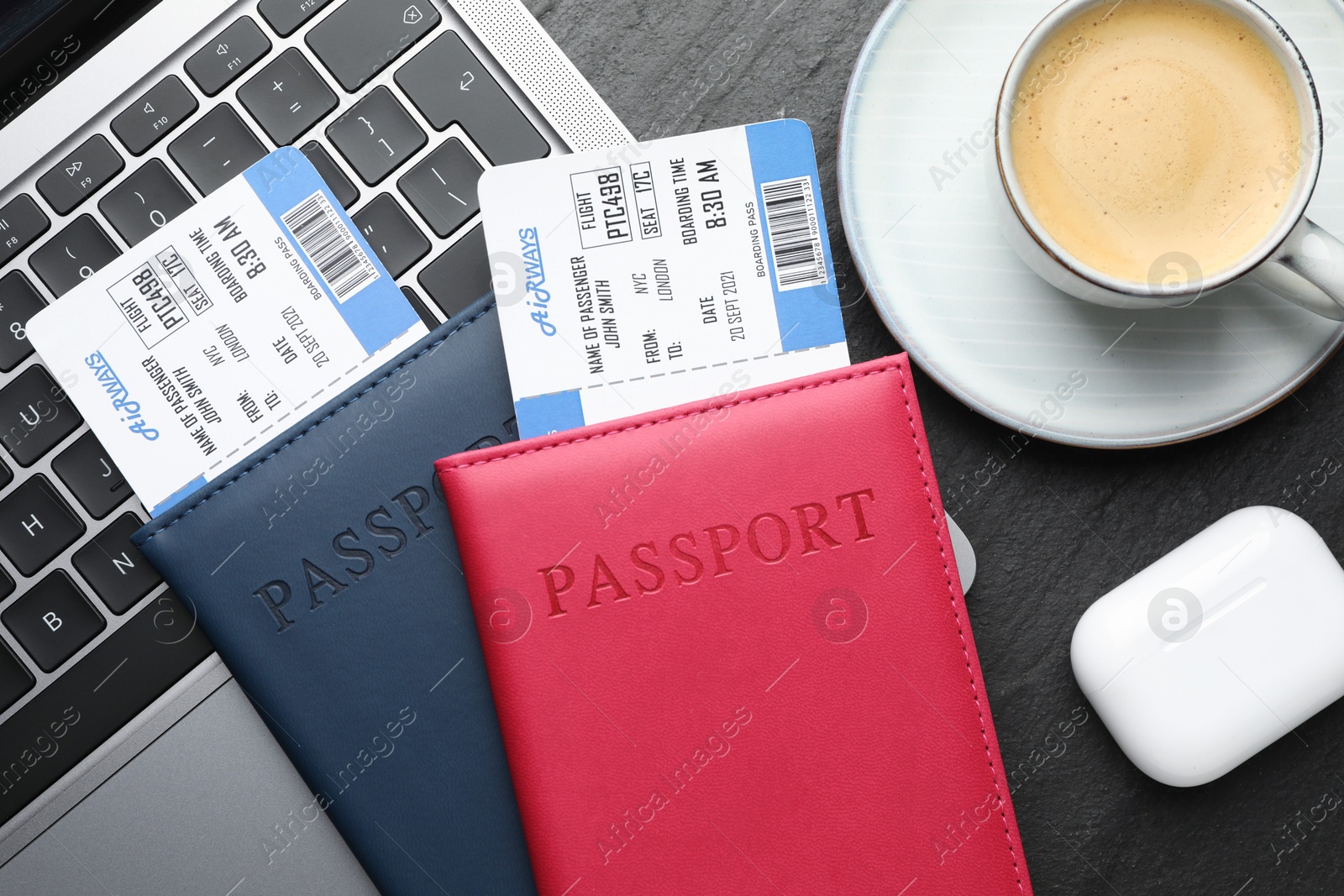 Photo of Travel agency. Flight tickets, passports, laptop and cup of coffee on dark textured table, flat lay