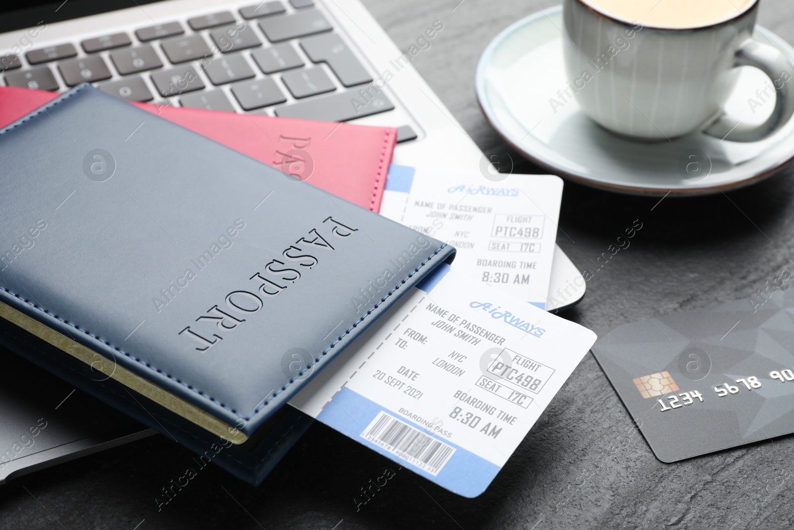 Photo of Travel agency. Flight tickets, passports, laptop and credit card on dark textured table, closeup