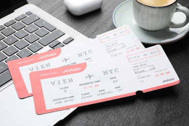 Photo of Travel agency. Flight tickets, laptop and cup on dark textured table, closeup