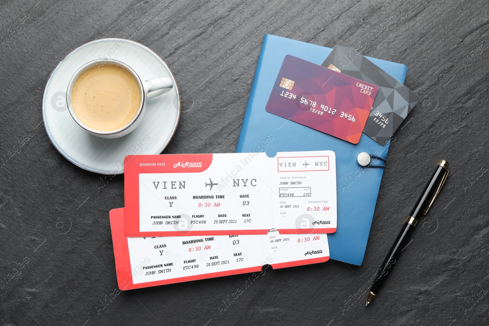 Photo of Travel agency. Flight tickets, credit cards, stationery and cup of coffee on dark textured table, flat lay