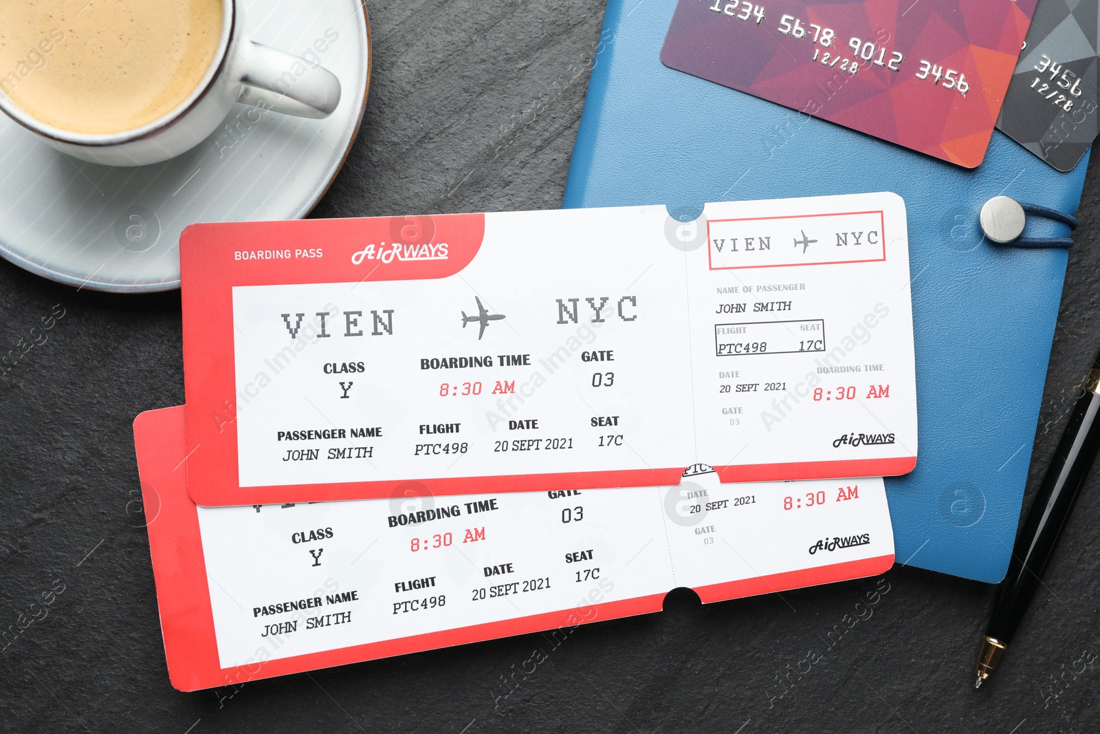 Photo of Travel agency. Flight tickets, credit cards, stationery and cup of coffee on dark textured table, flat lay