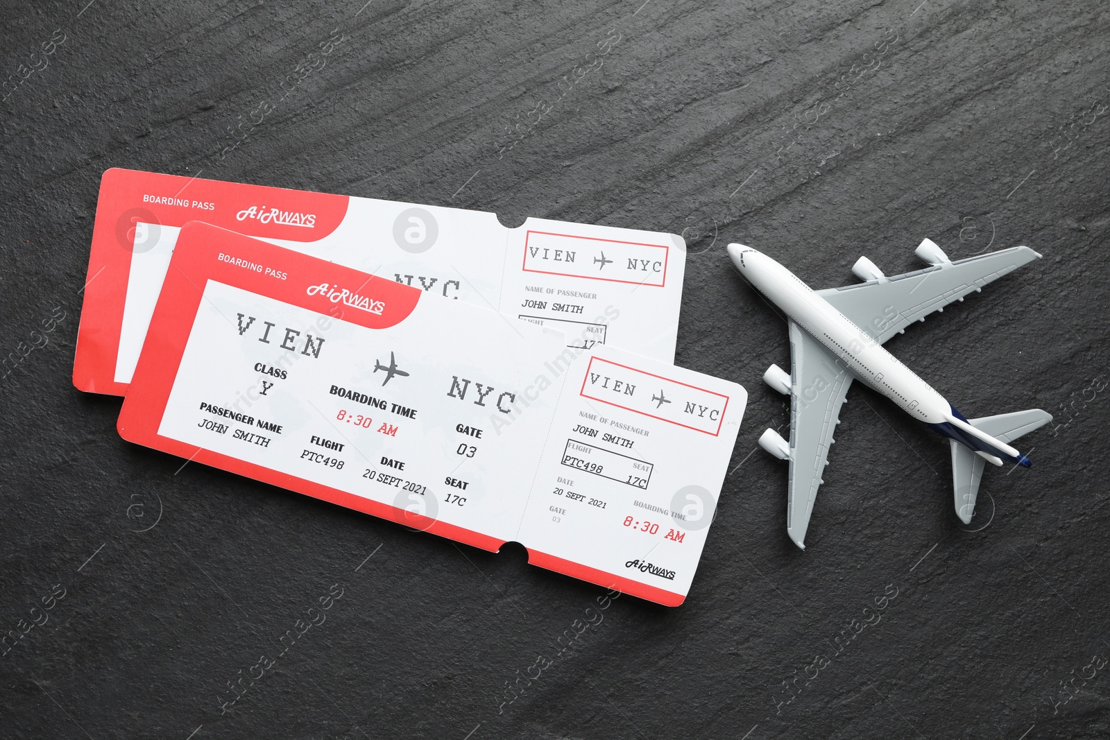 Photo of Travel agency. Flight tickets and plane model on dark textured table, flat lay