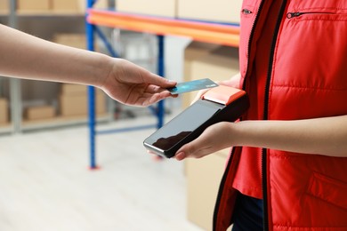 Photo of Woman paying for service with credit card via terminal indoors, closeup