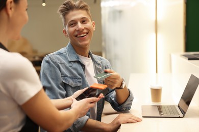 Photo of Man paying with credit card via terminal in cafe