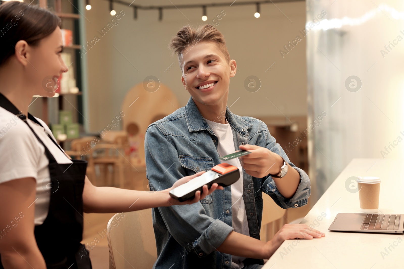 Photo of Man paying with credit card via terminal in cafe