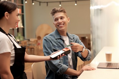 Man paying with credit card via terminal in cafe