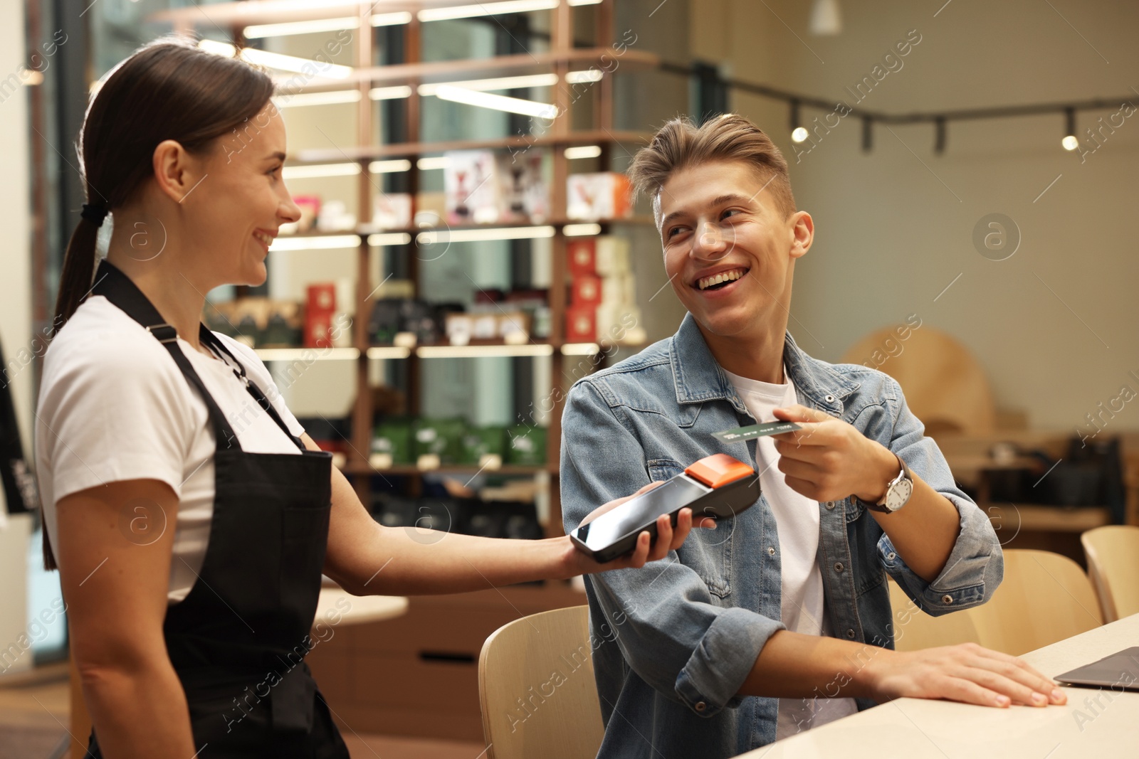 Photo of Man paying with credit card via terminal in cafe