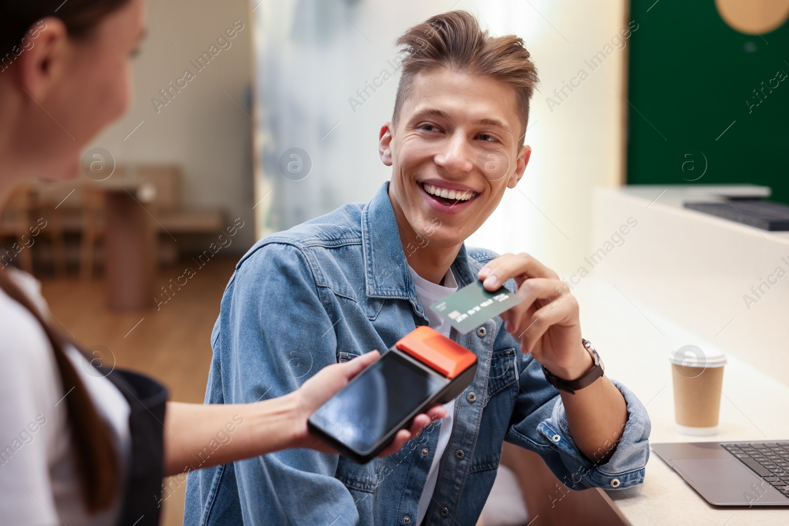 Photo of Man paying with credit card via terminal in cafe