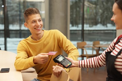 Photo of Man paying with credit card via terminal in cafe