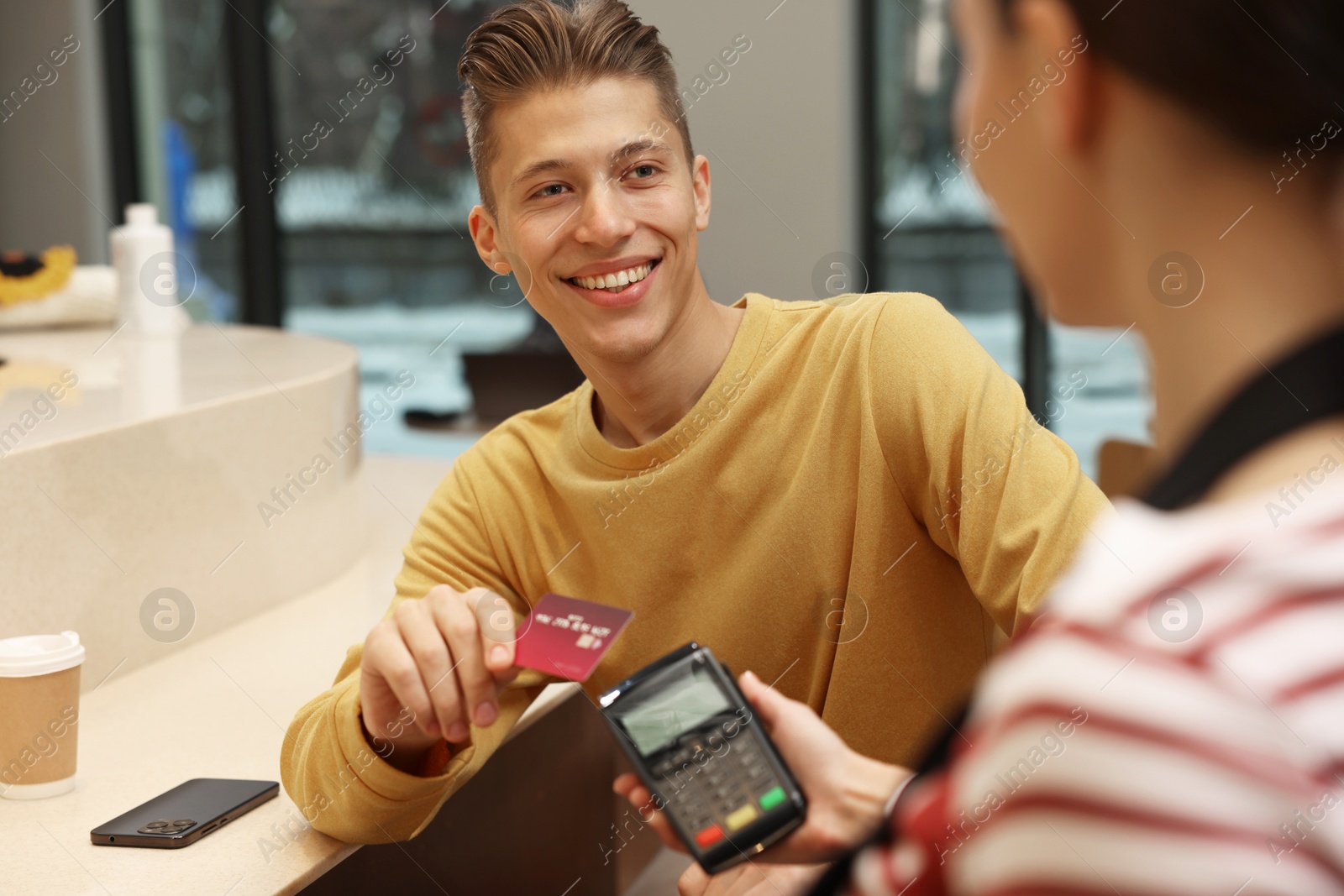 Photo of Man paying with credit card via terminal in cafe