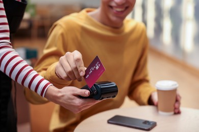 Photo of Man paying with credit card via terminal in cafe, closeup