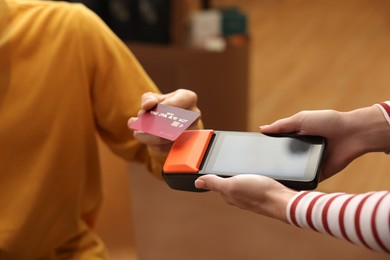 Photo of Man paying with credit card via terminal in cafe, closeup