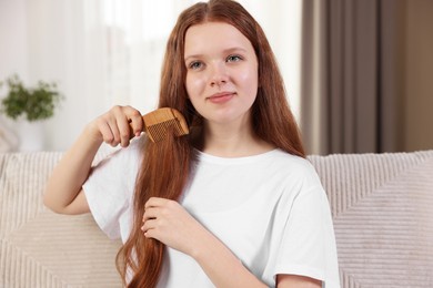 Photo of Beautiful teenage girl brushing her hair with comb at home