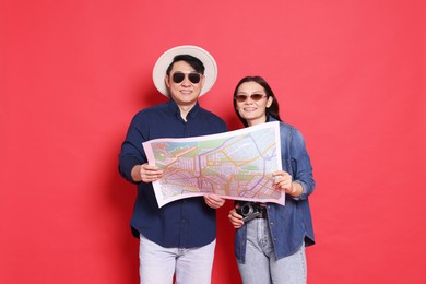 Photo of Happy travellers with map on red background