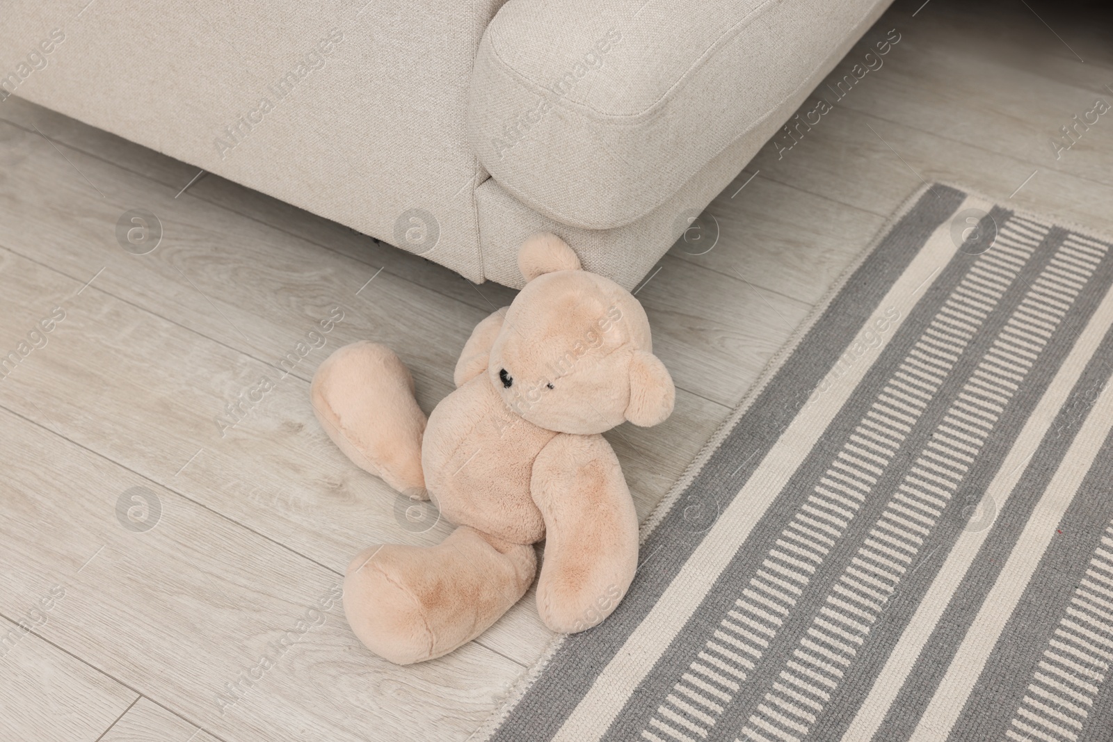 Photo of Teddy bear near sofa on floor in room