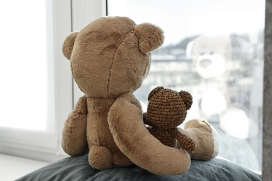 Photo of Two cute teddy bears near window indoors. back view