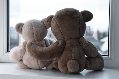 Photo of Two cute teddy bears near window indoors, back view