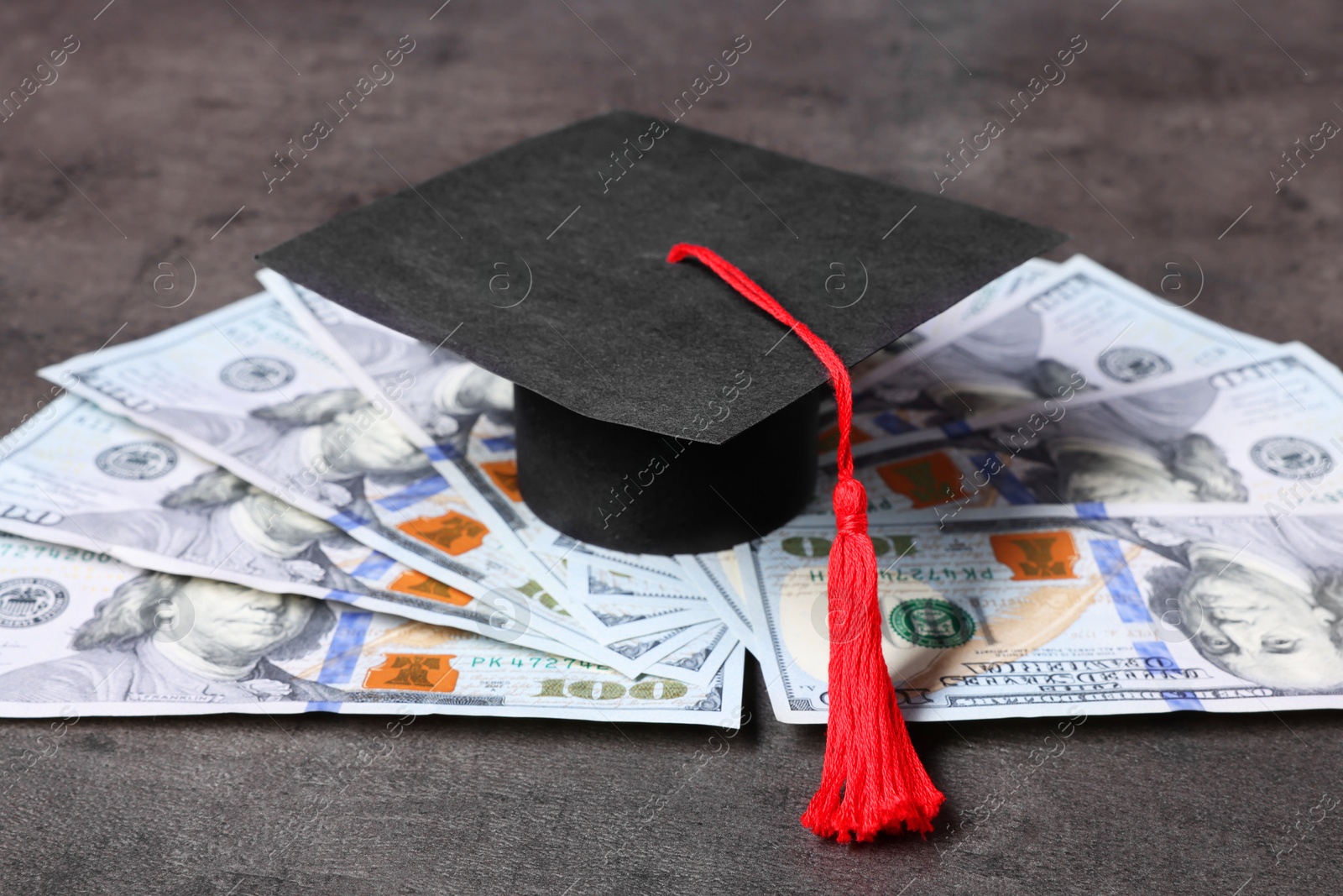 Photo of Graduate hat and dollars on grey textured table. Tuition payment