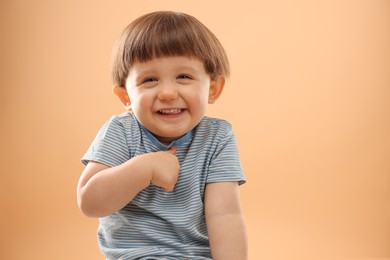 Photo of Portrait of happy little boy on beige background. Space for text