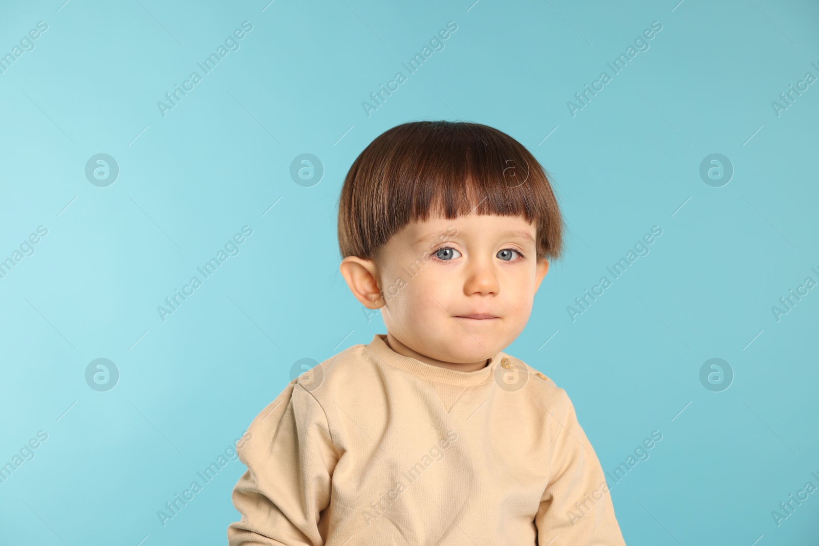 Photo of Portrait of cute little boy on light blue background