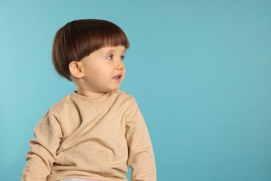 Photo of Portrait of cute little boy on light blue background. Space for text