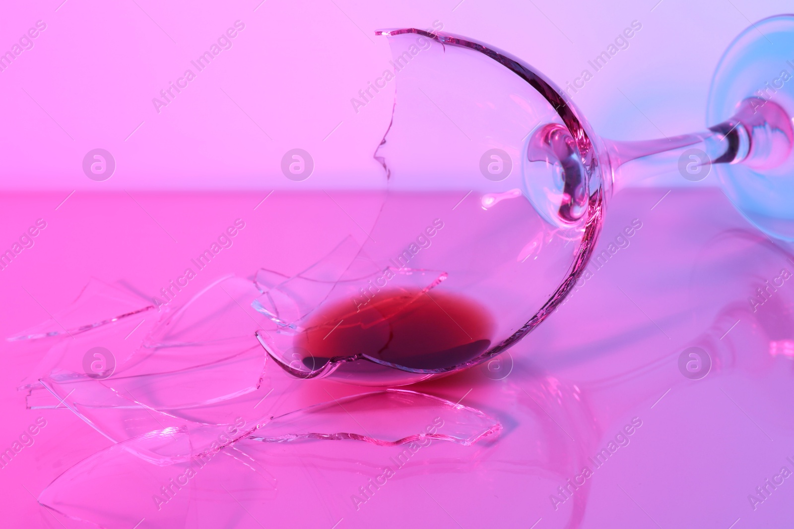 Photo of Pieces of broken glass with wine on table, closeup. Color tone effect