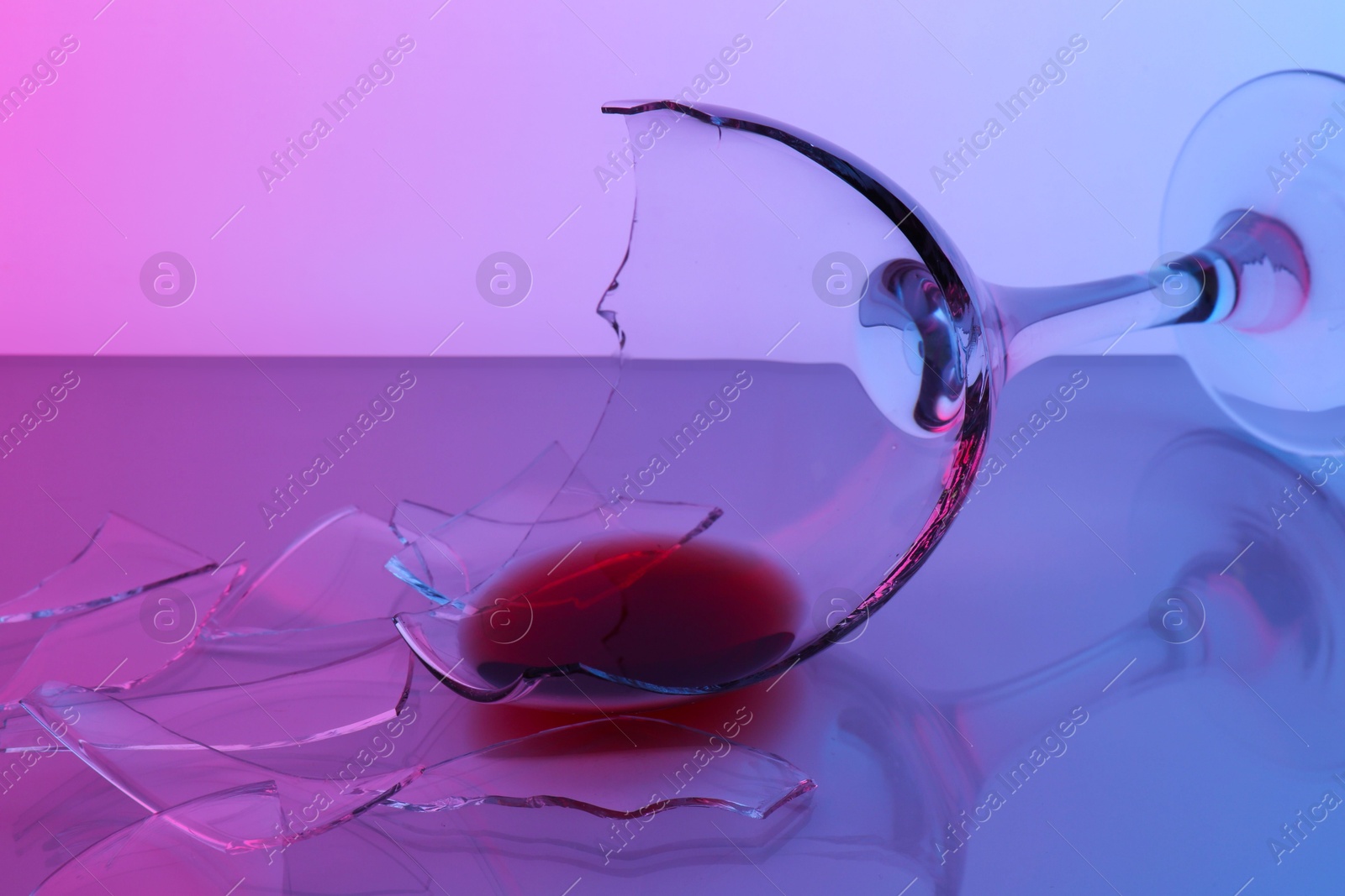 Photo of Pieces of broken glass with wine on table, closeup. Color tone effect