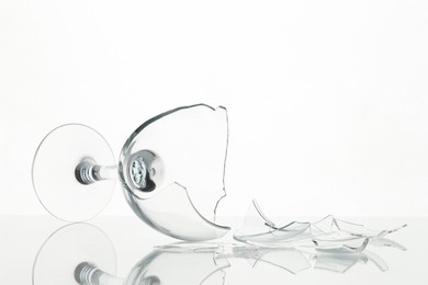 Photo of Pieces of broken wine glass on table against white background, closeup