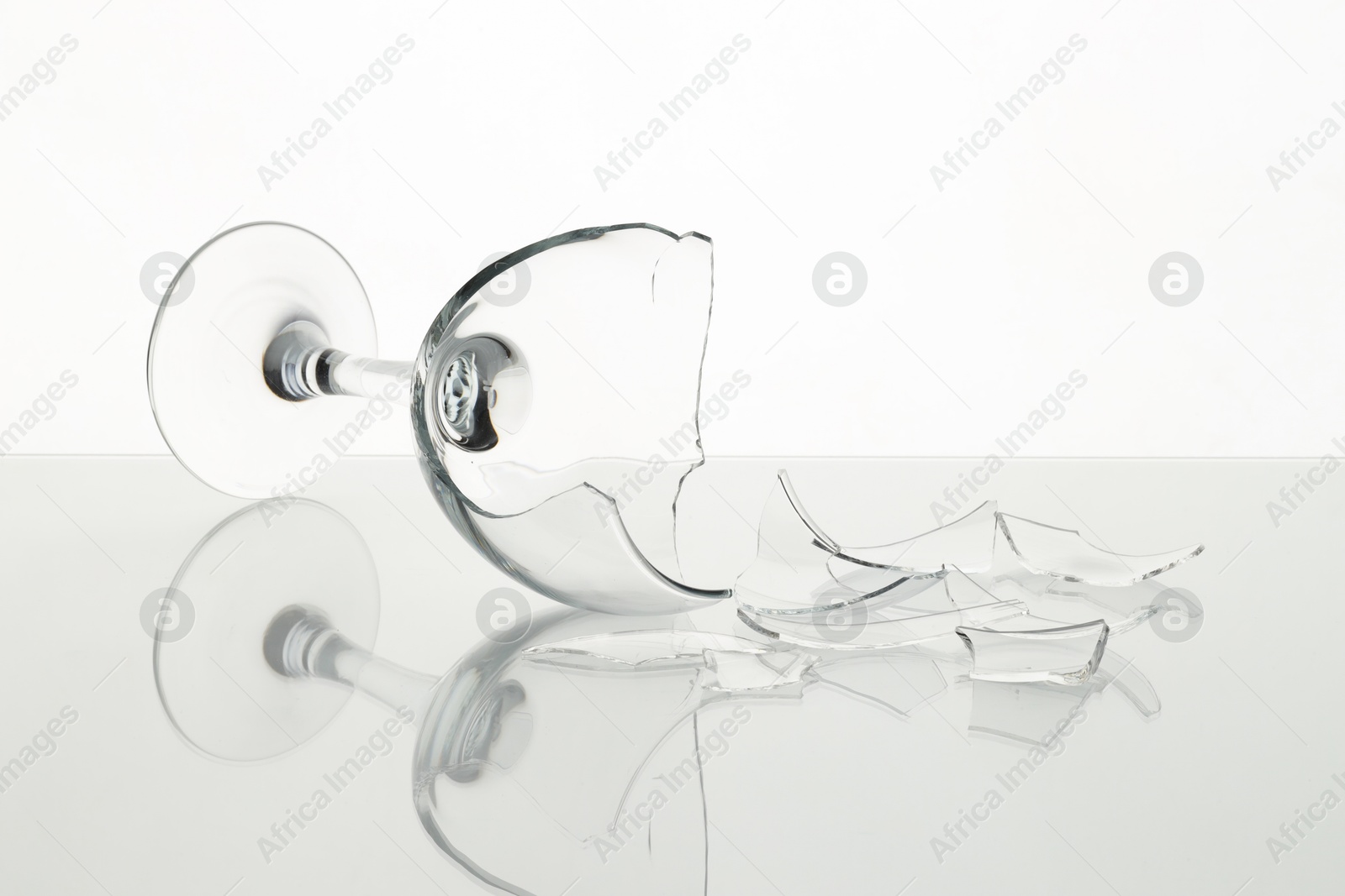 Photo of Pieces of broken wine glass on table against white background