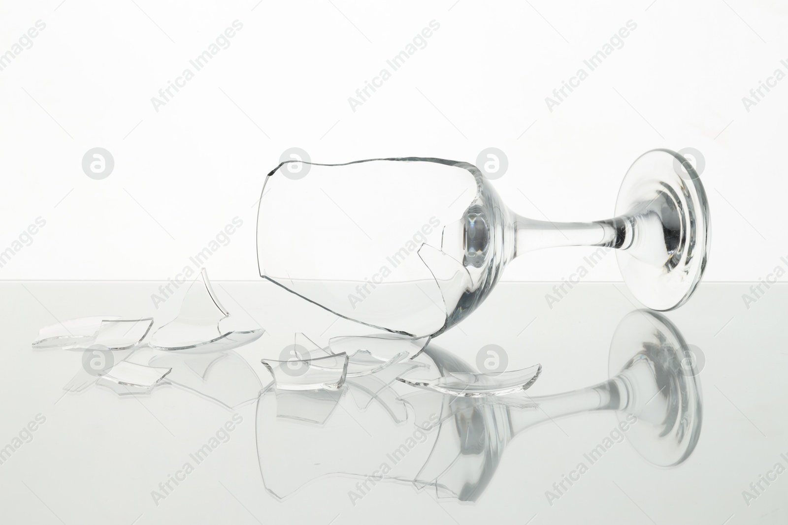 Photo of Pieces of broken wine glass on table against white background