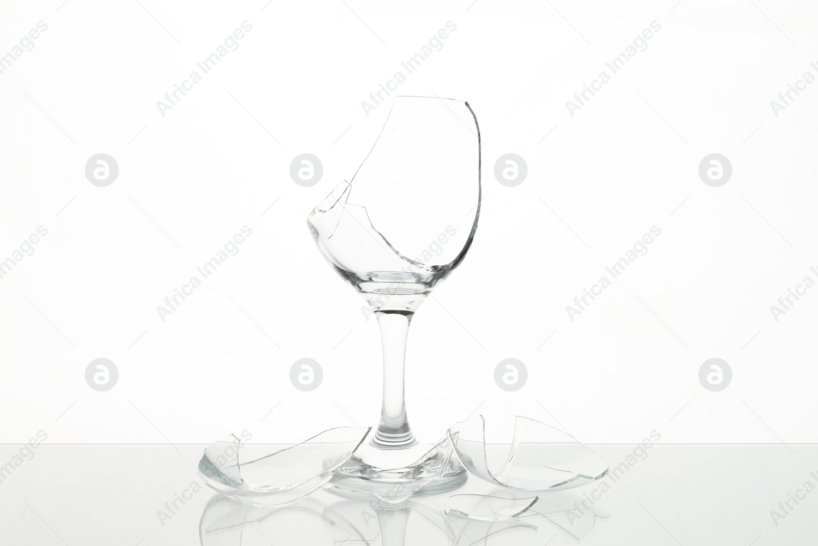 Photo of Pieces of broken wine glass on table against white background