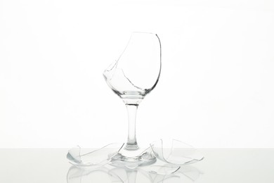 Photo of Pieces of broken wine glass on table against white background