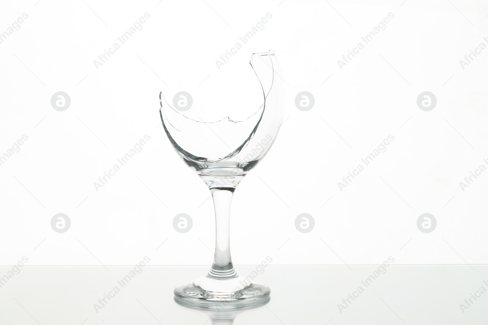 Photo of One broken wine glass on table against white background