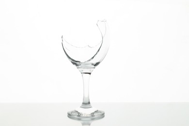 Photo of One broken wine glass on table against white background