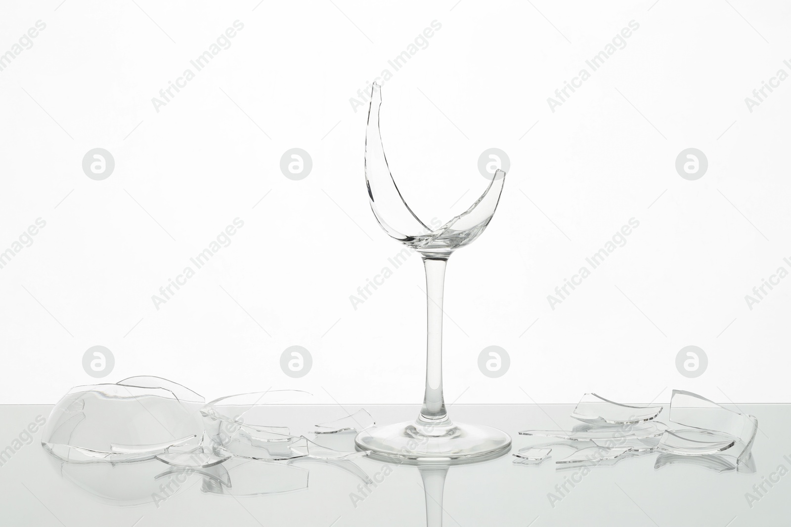 Photo of Pieces of broken wine glass on table against white background