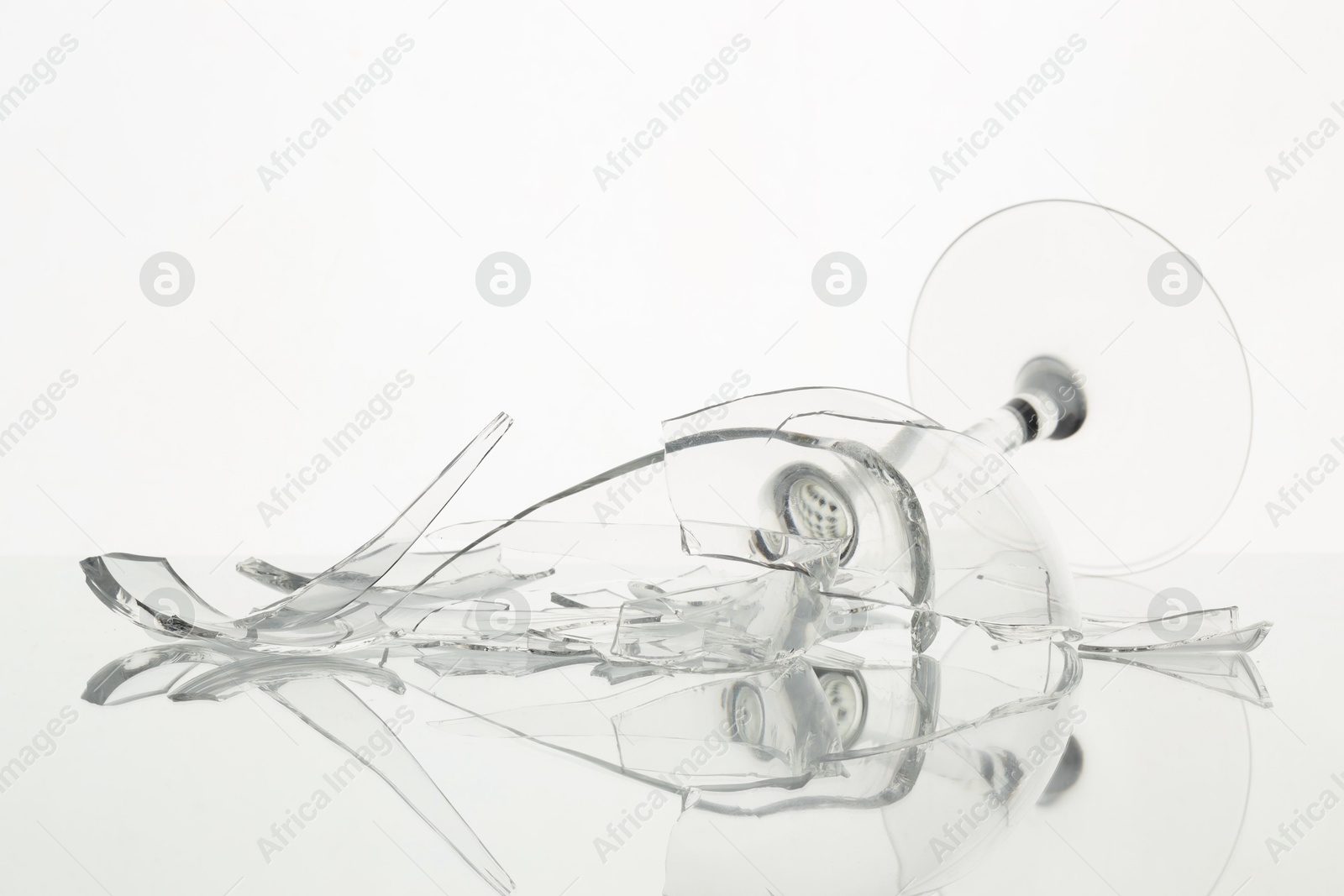 Photo of Pieces of broken wine glass on table against white background, closeup