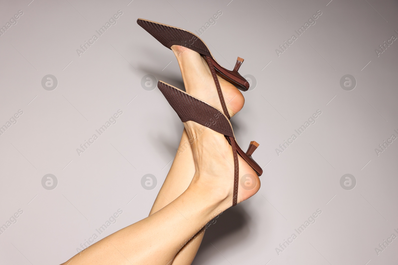 Photo of Woman wearing beautiful brown shoes on light grey background, closeup