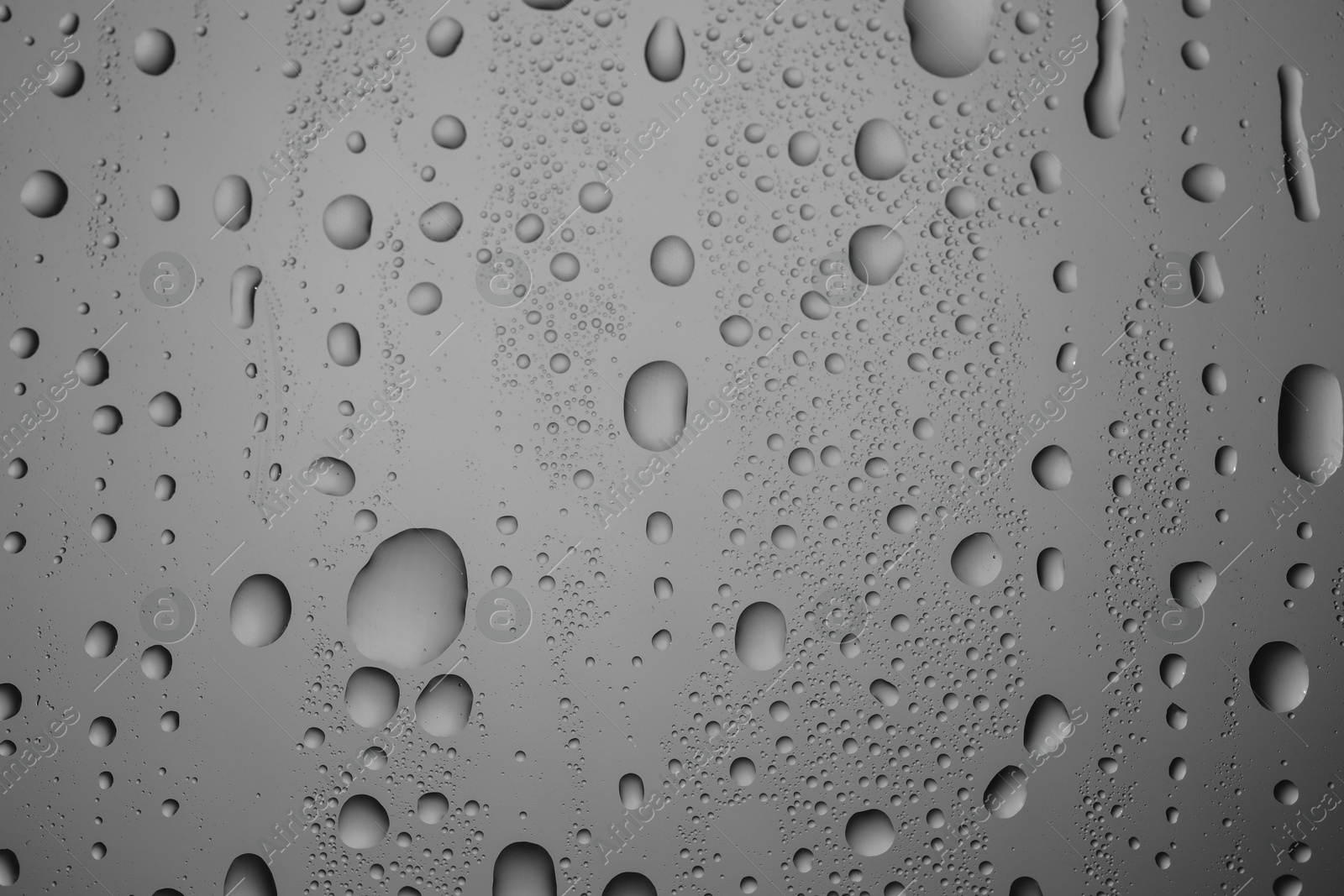 Photo of Water drops on grey glass surface, top view