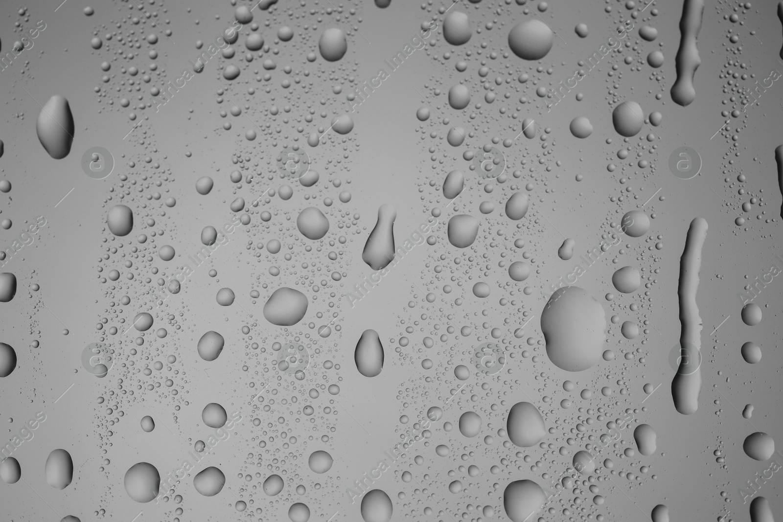 Photo of Water drops on grey glass surface, top view