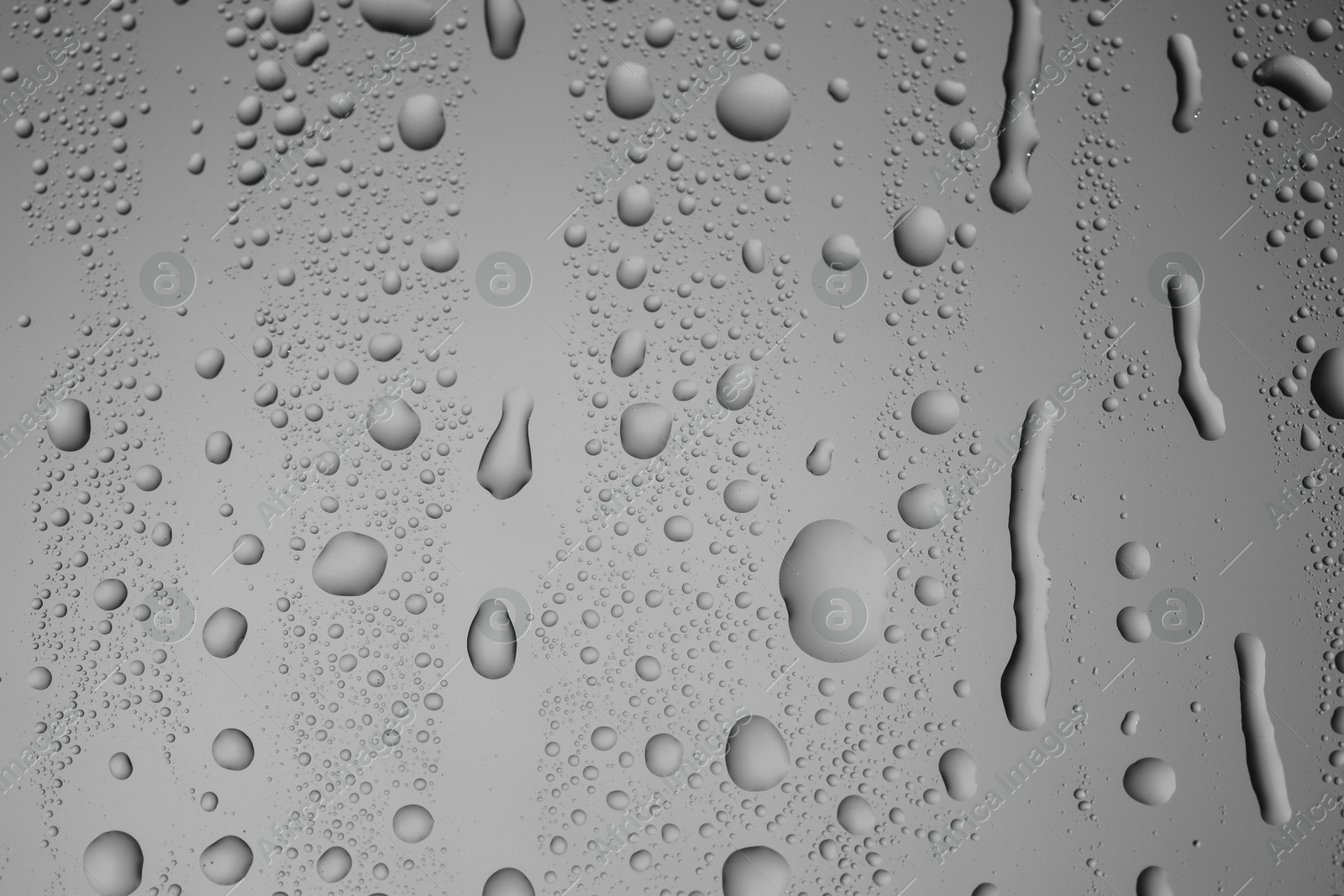 Photo of Water drops on grey glass surface, closeup