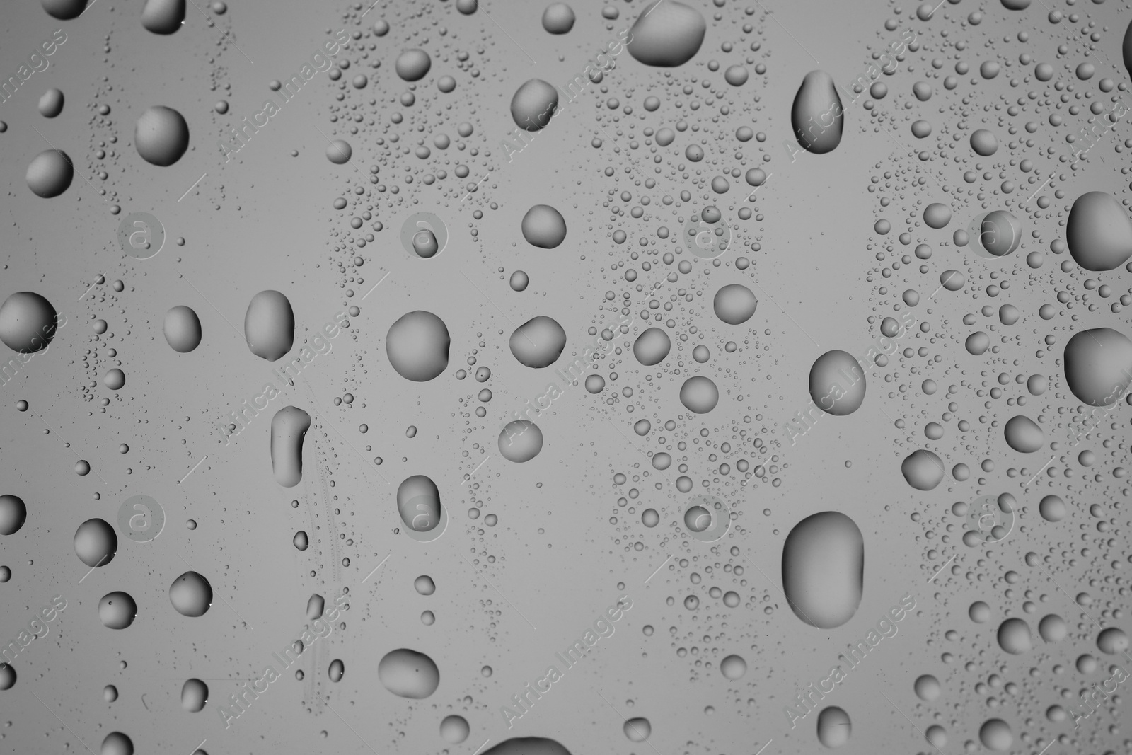 Photo of Water drops on grey glass surface, top view