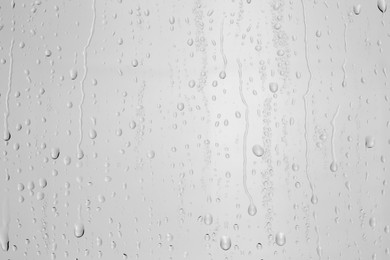 Photo of Water drops on light grey glass surface, top view