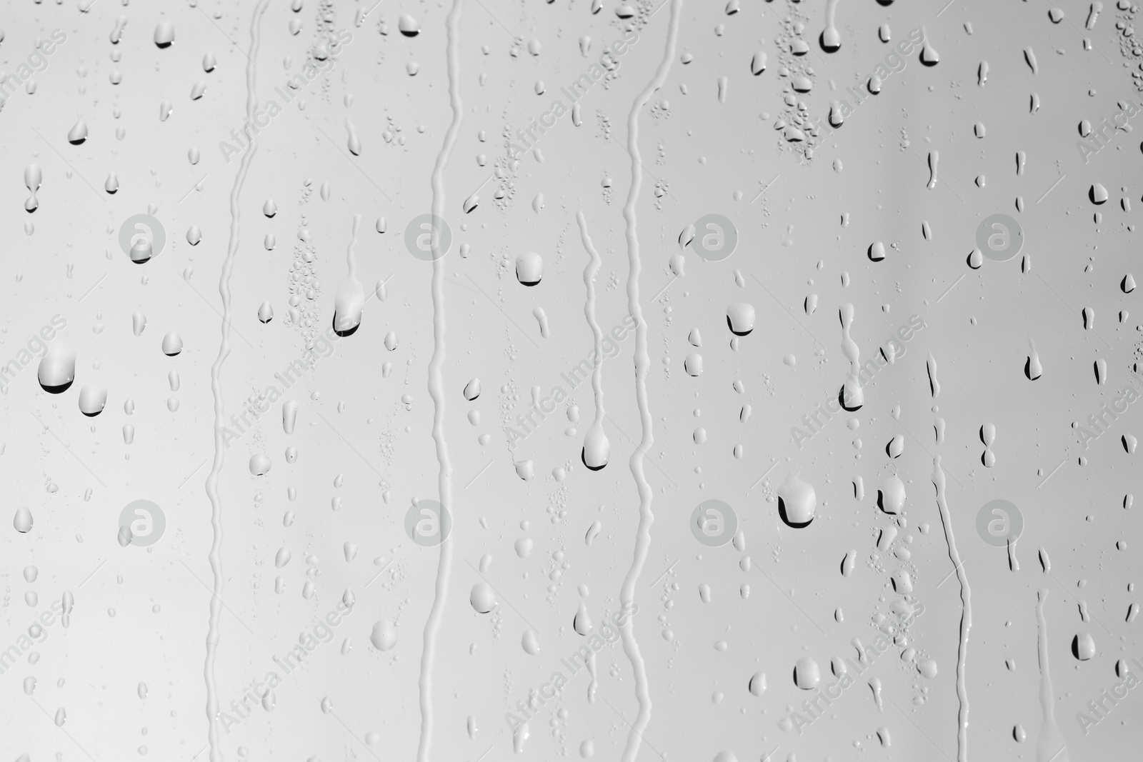 Photo of Water drops on light grey glass surface, closeup