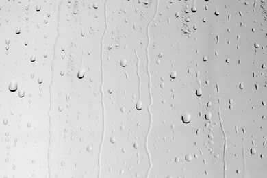 Water drops on light grey glass surface, closeup