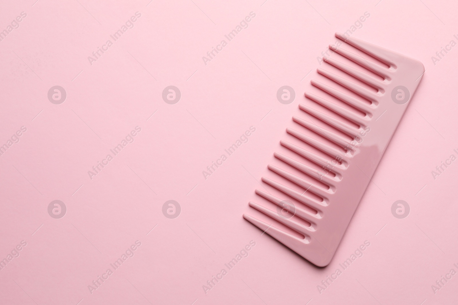 Photo of One plastic hair comb on pink background, top view. Space for text