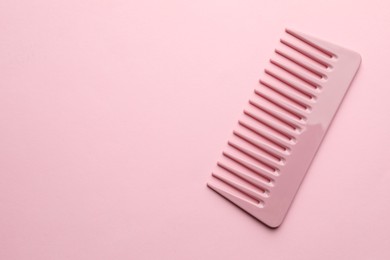 Photo of One plastic hair comb on pink background, top view. Space for text