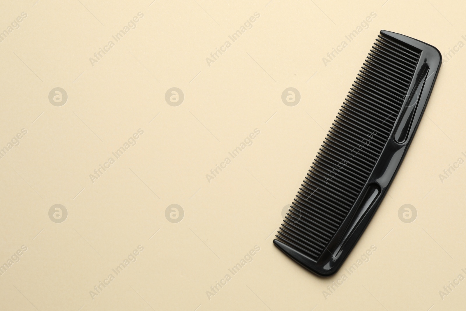 Photo of One black plastic comb on beige background, top view. Space for text