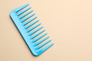 Photo of One light blue plastic comb on beige background, top view. Space for text