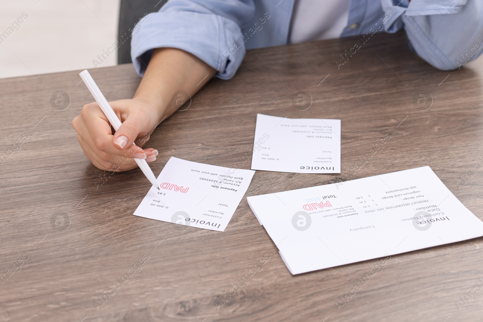 Photo of Paying bills. Woman with different invoices at wooden table indoors, closeup